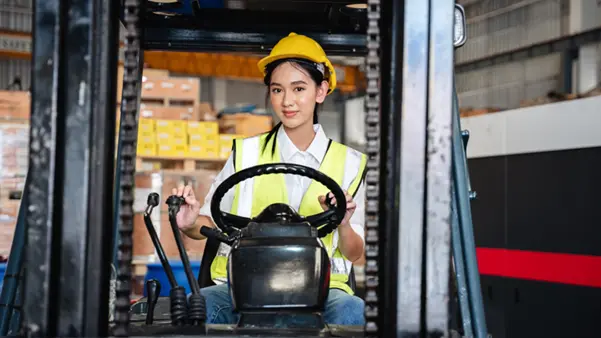 A trained female operator driving a diesel forklift A trained female operator driving a diesel forklift