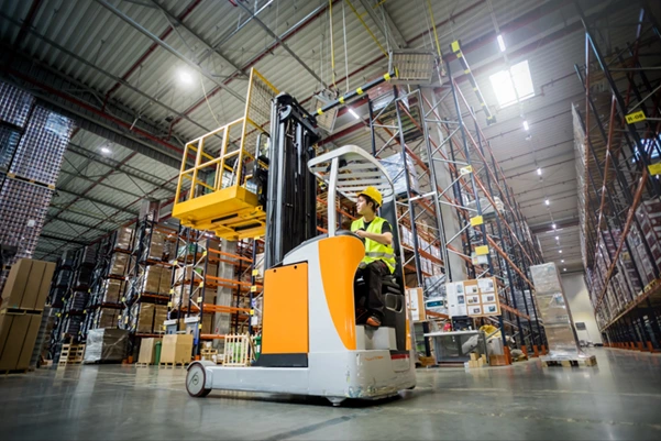 An operator using a reach truck to lift a pallet in a high-density warehouse aisle An operator using a reach truck to lift a pallet in a high-density warehouse aisle