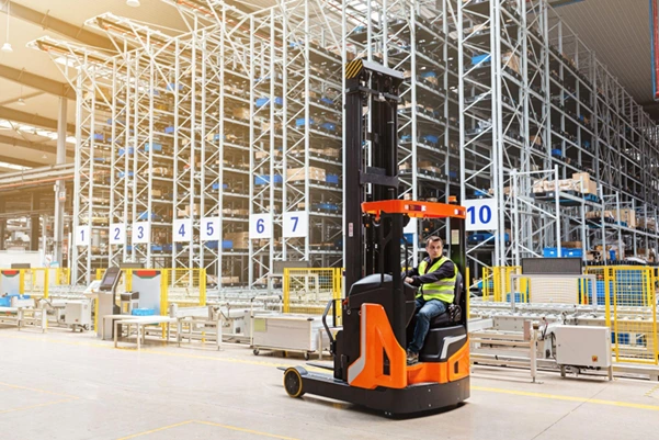 An operator on a reach truck lifting a pallet on high racking in a modern warehouse An operator on a reach truck lifting a pallet on high racking in a modern warehouse