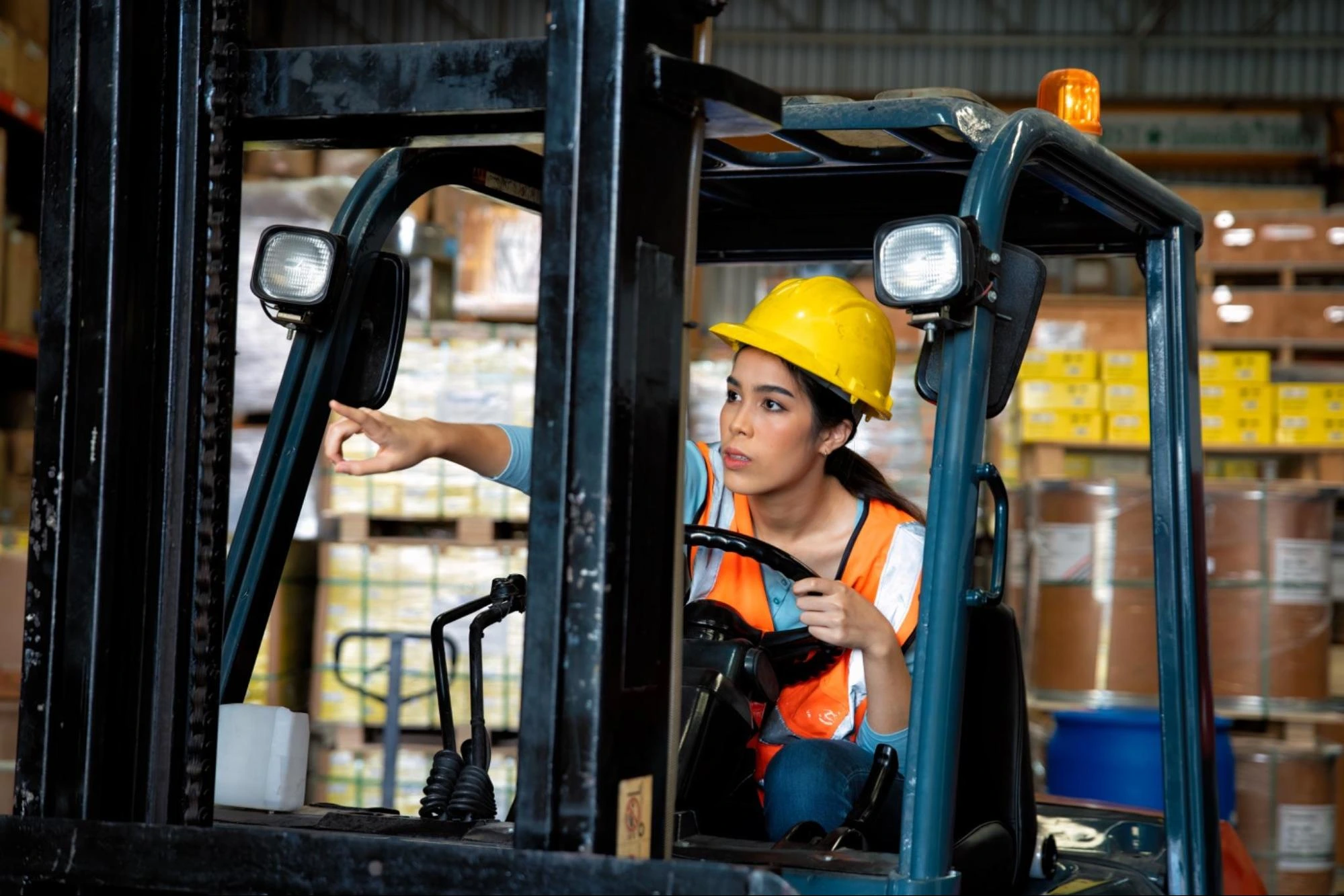 Forklift Terrain and Environment Considerations A forklift operator wearing a hard hat looking out from the forklift cabin