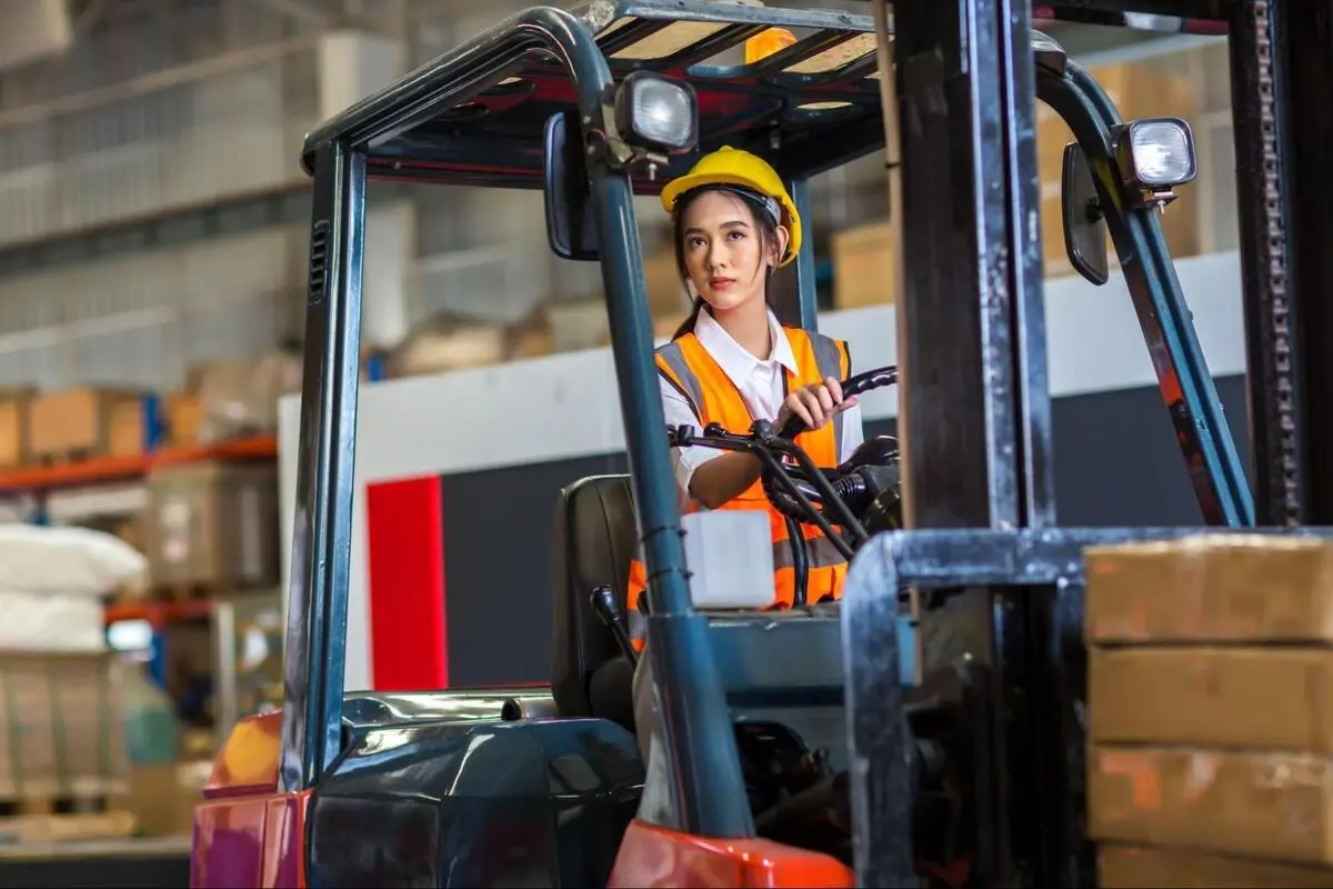 Forklift Operator Handling Cargo in Warehouse Warehouse worker driving a forklift while handling stacked boxes inside an industrial warehouse.