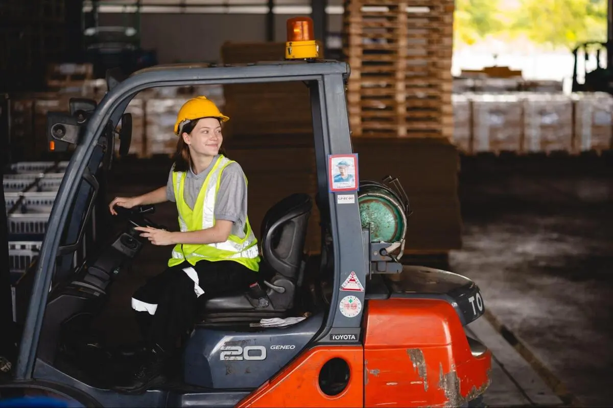 Warehouse Worker Operating a Forklift Indoors Warehouse worker operating a forklift inside a warehouse with stacked pallets in the background
