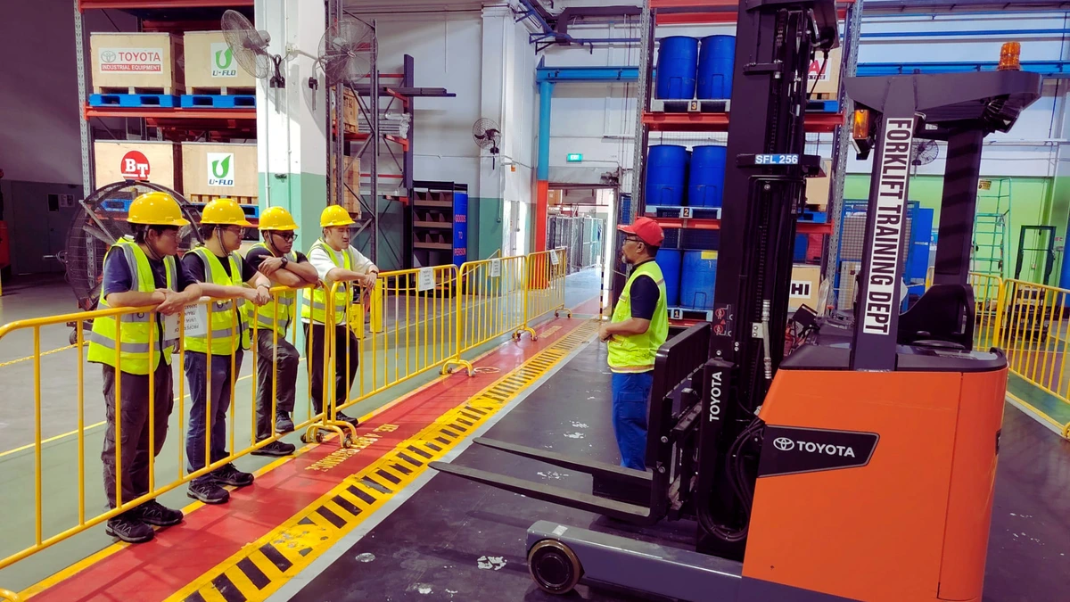 Forklift training practice in Singapore Forklift training practice in Singapore with trainees learning safe forklift operation in a warehouse setting.