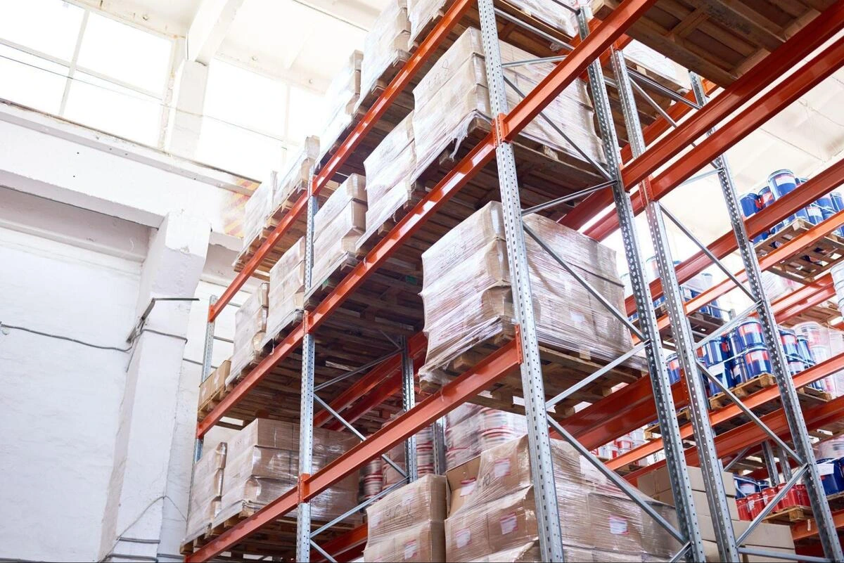 Industrial Storage Racking in a Singapore Distribution Centre Upward perspective of a high-rise industrial storage racking system holding shrink-wrapped stock, configured for vertical fleet clearance and advanced forklift training drills.