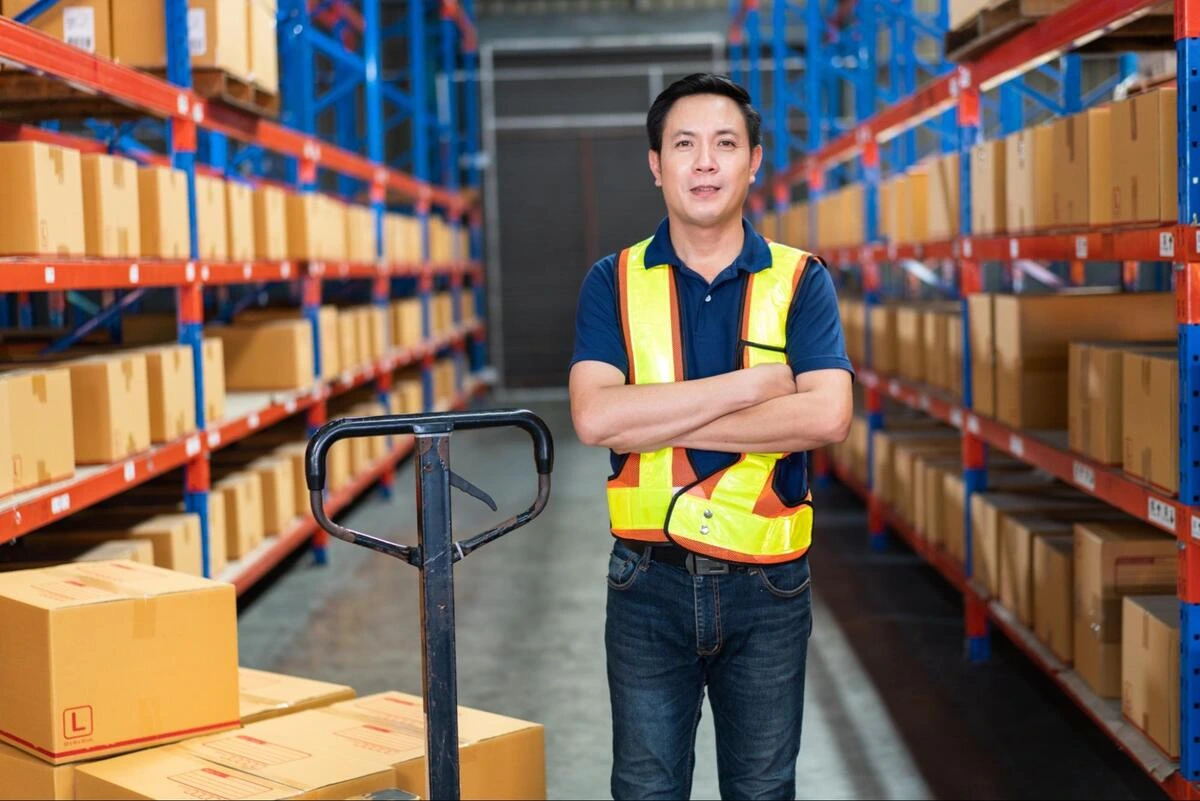 A warehouse worker stands between industrial racking